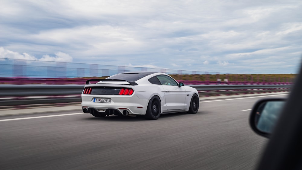 a white sports car driving down a highway