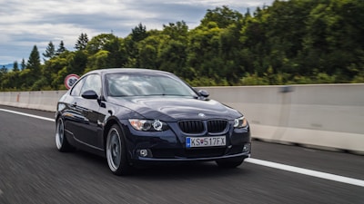 A BMW driving along a scenic coastal road under clear skies.