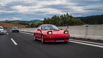 A red Audi cruising along a scenic highway with hills in the background.