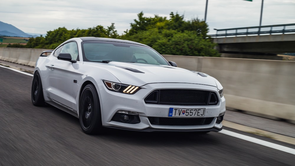 a white ford mustang driving down a highway