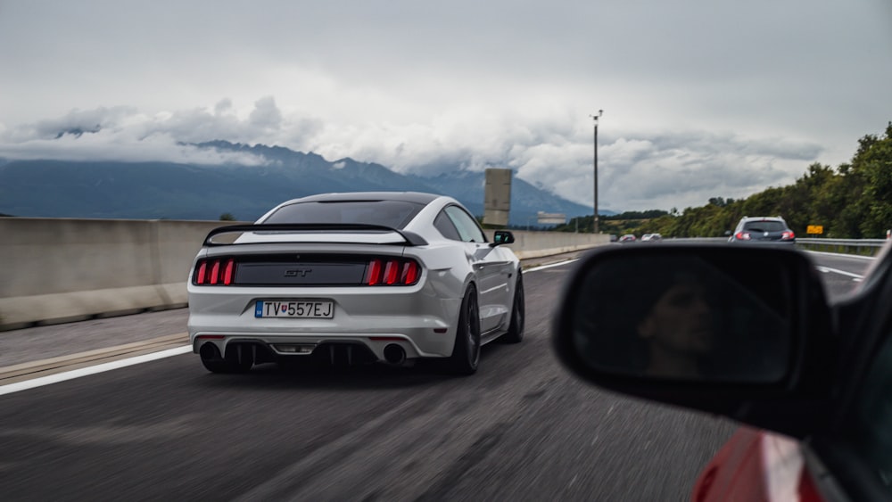 a white sports car driving down a highway