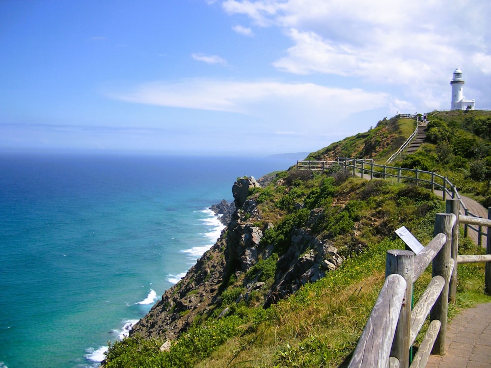 a wooden bench sitting on the side of a cliff next to the ocean