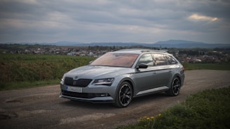 A sleek European estate car parked by a scenic countryside road with luggage loaded in the spacious rear.