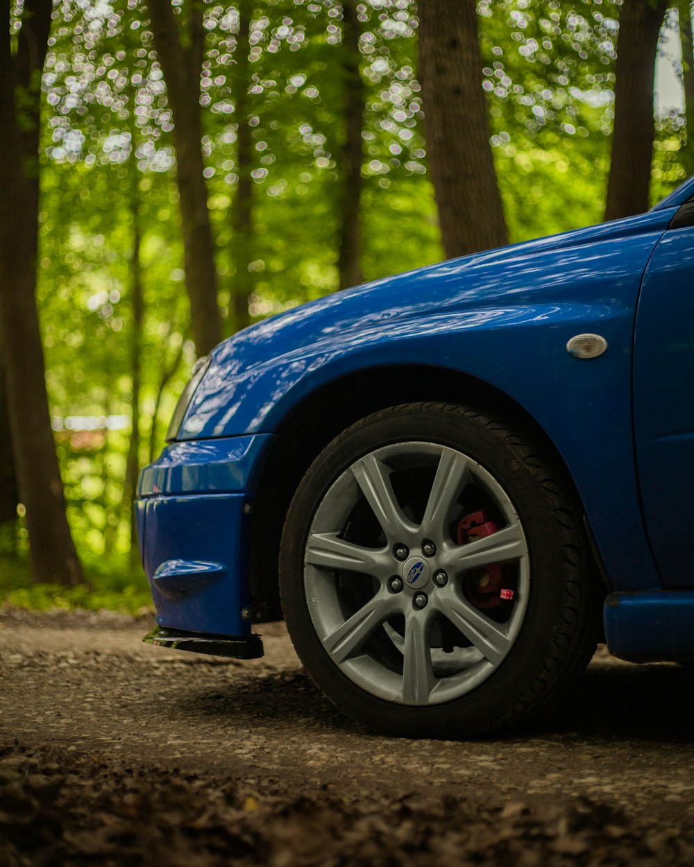 a blue car parked in a wooded area