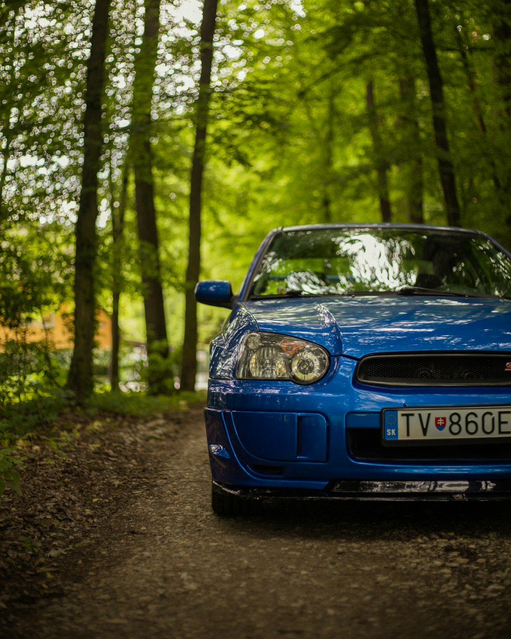 a blue car parked in the middle of a forest