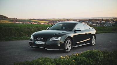 Sleek black German luxury sedan parked on a scenic UK countryside road.