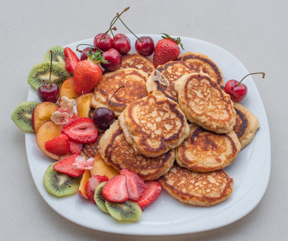 a white plate topped with pancakes and fruit