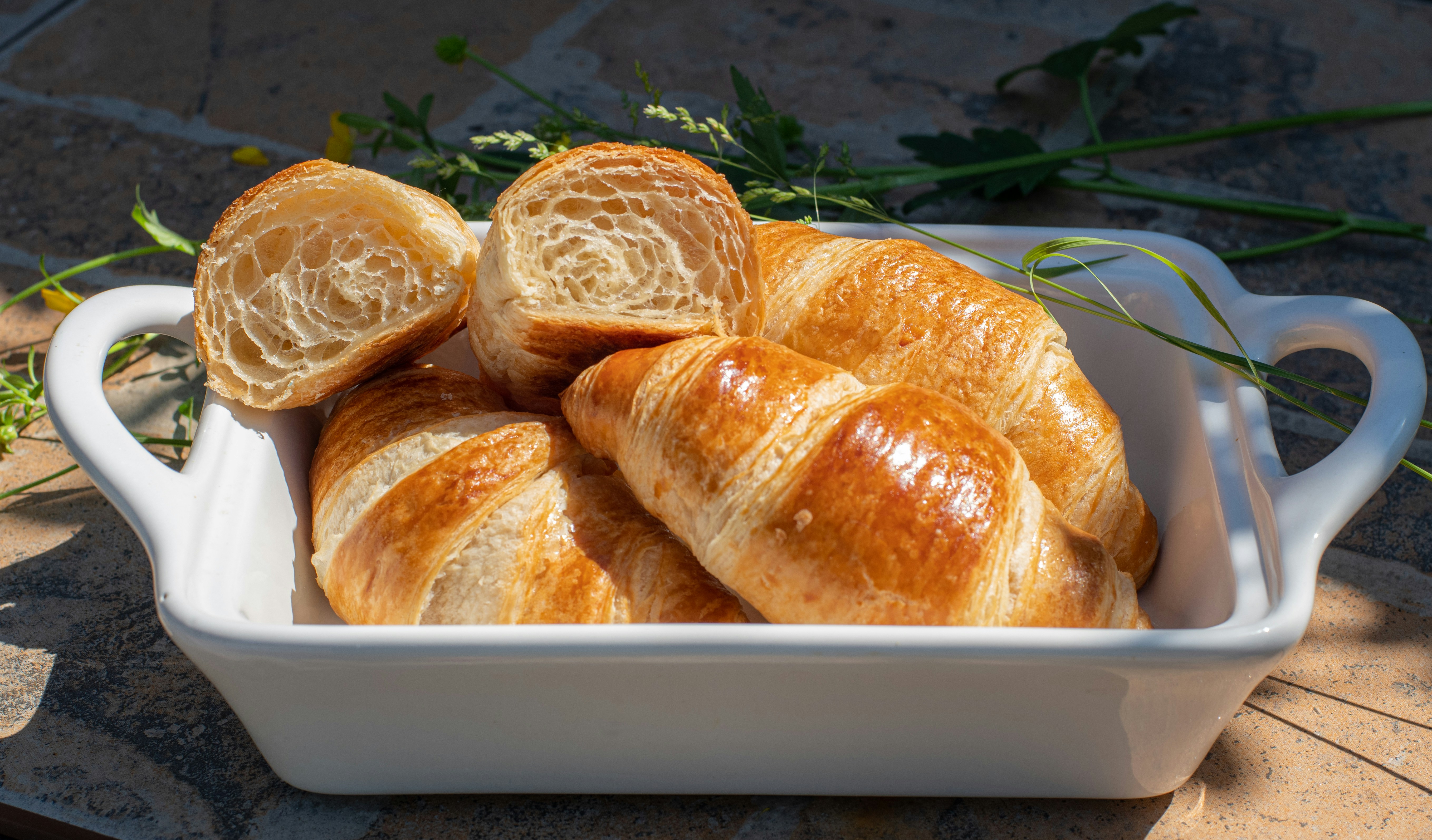 a white dish filled with croissants sitting on top of a table