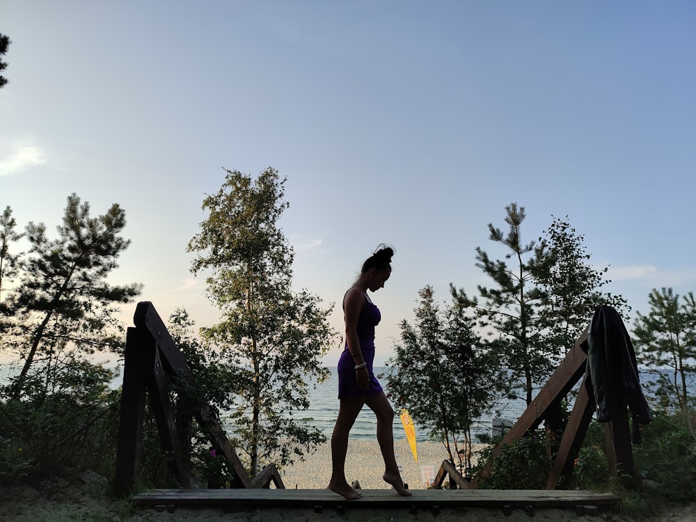 a woman in a bathing suit walking across a bridge