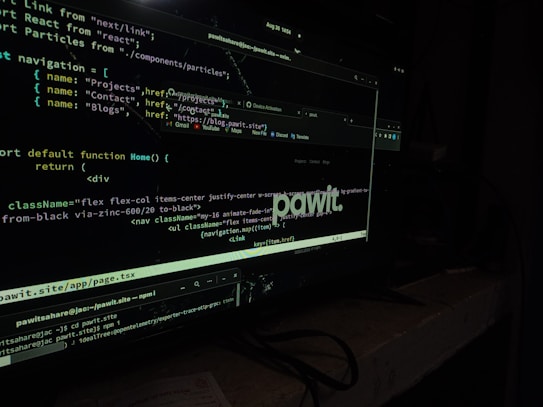 A computer screen displaying code in a dark-themed text editor. The code appears to be written in JavaScript, featuring functions and navigation links. There are file paths and command line interface windows open. A dark environment enhances the glow of the screen.