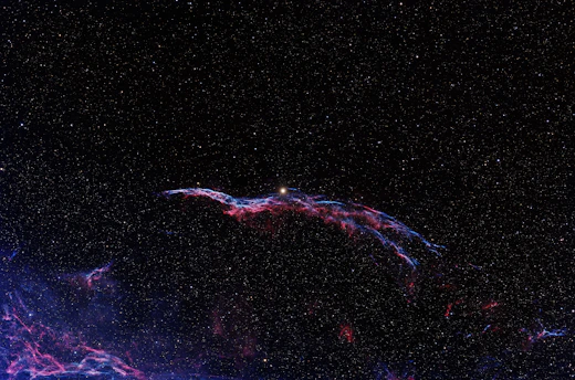 A glowing nebula swirling against a deep space black backdrop, with subtle silver stars scattered throughout.
