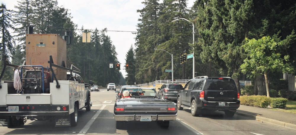 a white truck driving down a street next to a forest