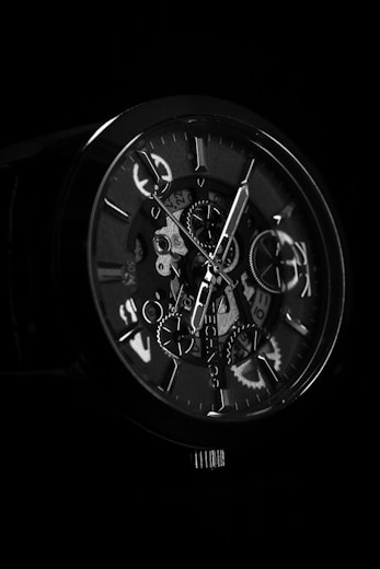 a black and white photo of a watch in the dark