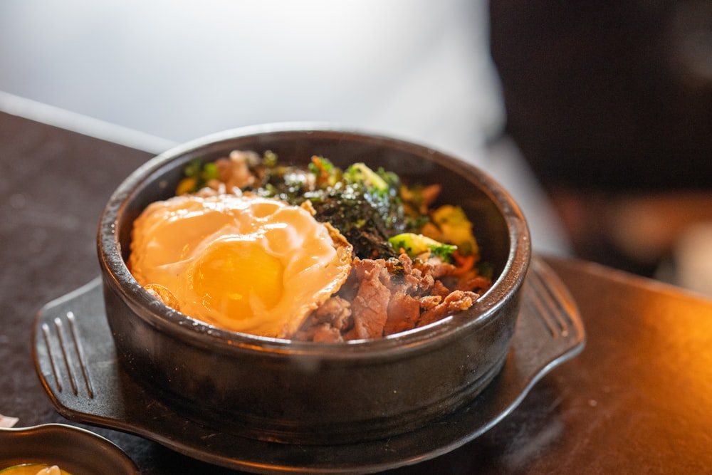 a bowl of food sitting on top of a wooden table