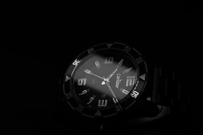 Close-up of a sleek wristwatch glowing under cinematic lighting on a dark background.