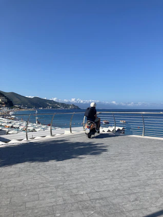 A happy traveler riding a blue scooter along a scenic Bali coastal road under clear skies.