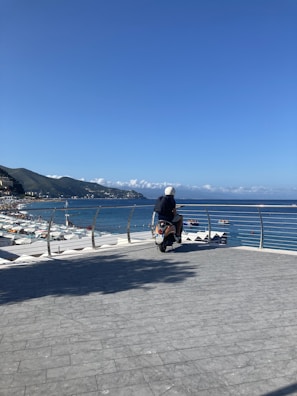 A rider wearing a helmet cruising along a coastal highway with ocean views.