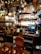 A cozy pub interior with various decorations, including British flags and beer taps prominently displayed. The bar countertop features several beer taps with different labels. Behind the bar, shelves are stocked with a variety of bottles and adorned with unique memorabilia and lights.