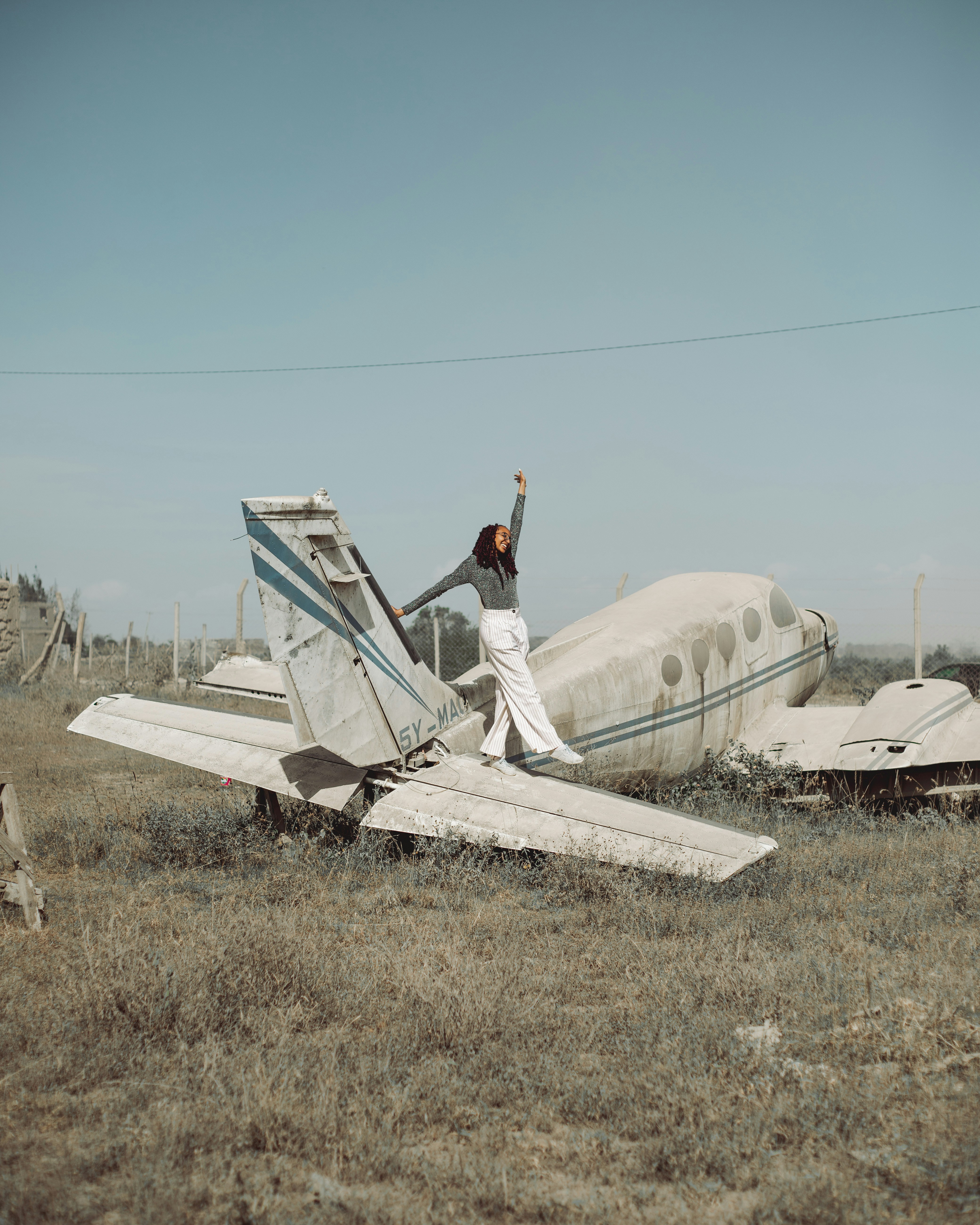a woman standing on top of a broken plane in a field