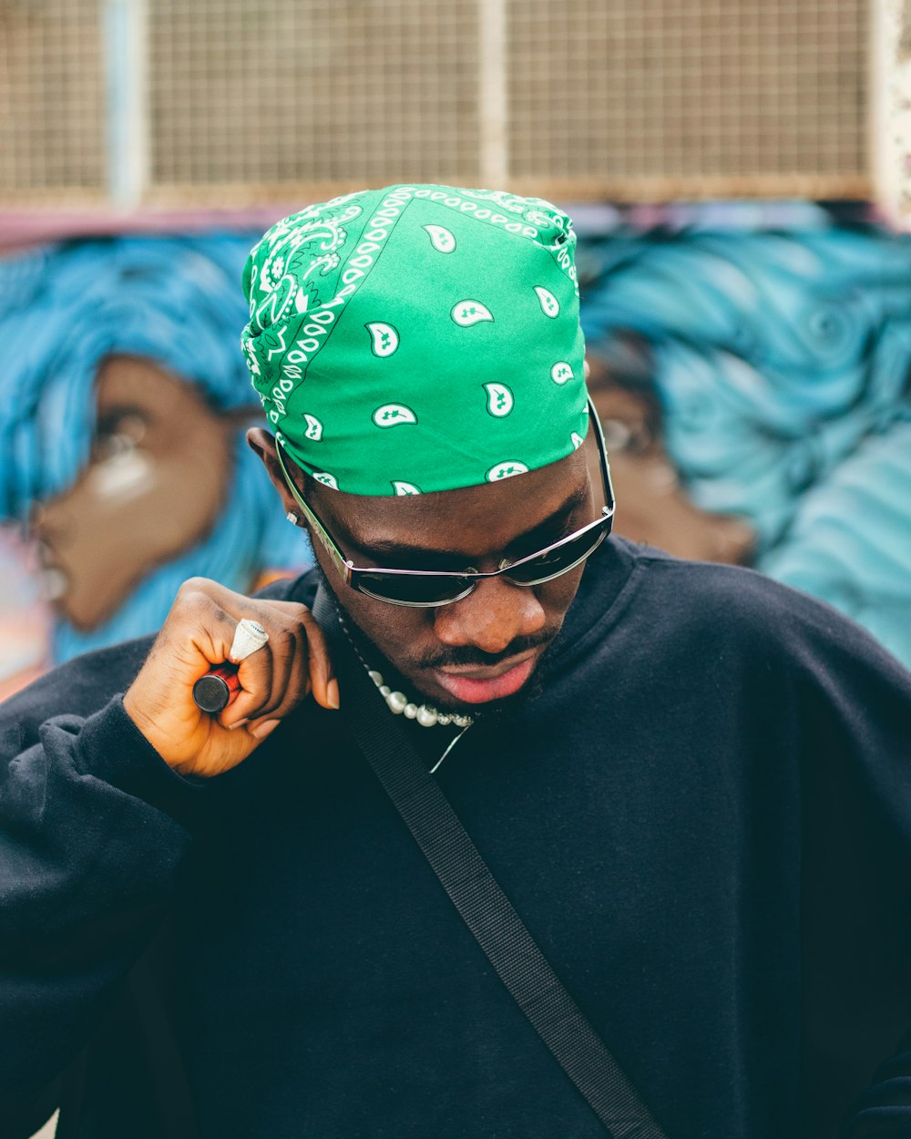 a man wearing a green bandana while talking on a cell phone
