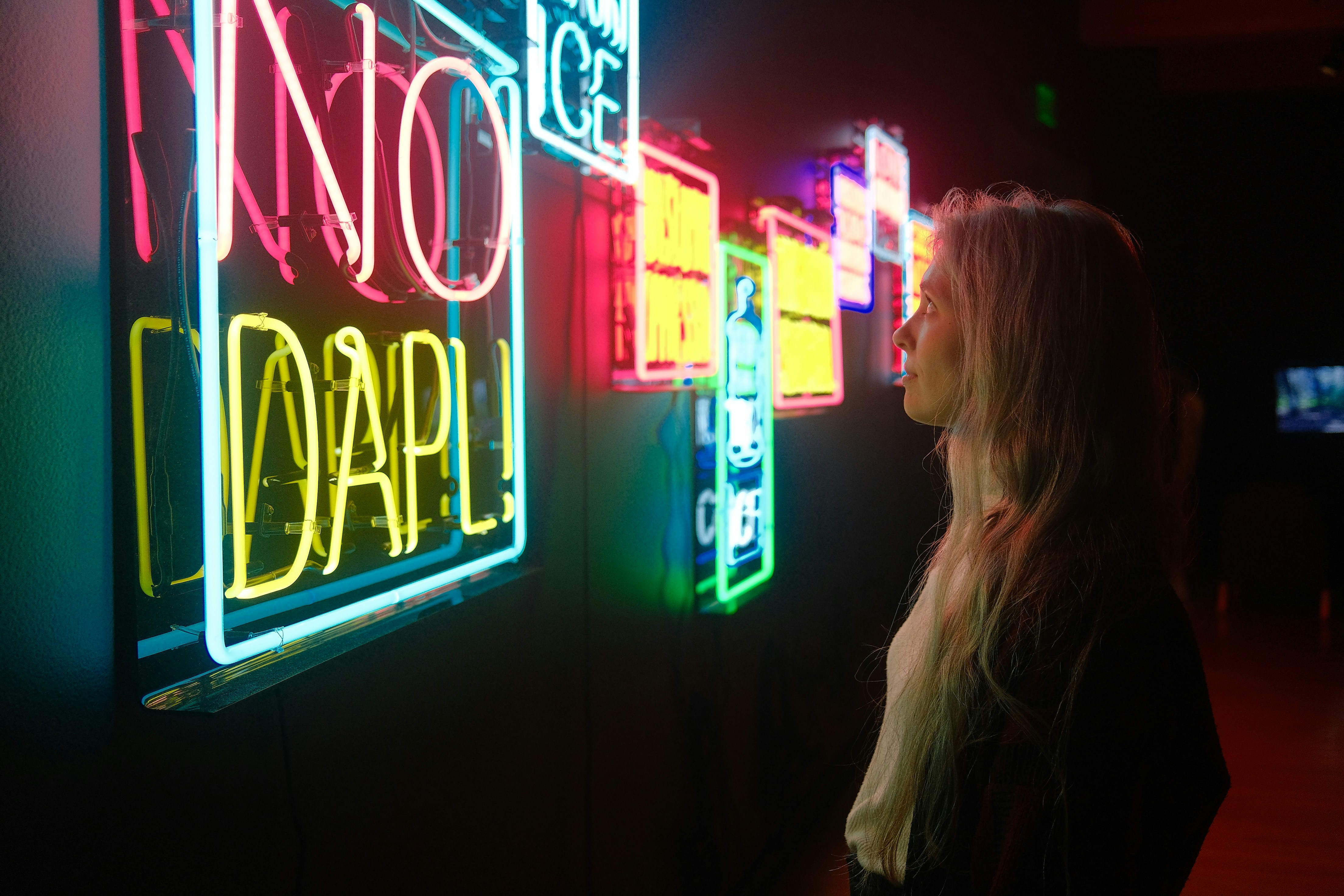 a woman standing in front of a neon sign