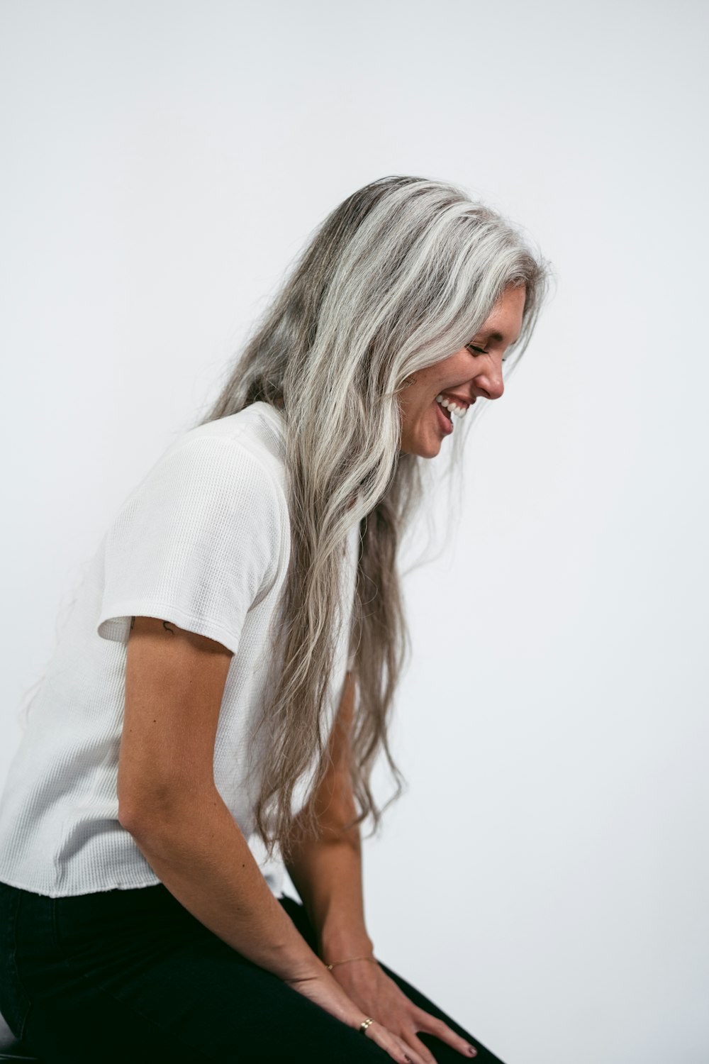 a woman with long white hair sitting on a stool