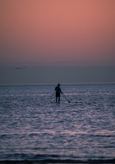 a man standing on a paddle board in the ocean