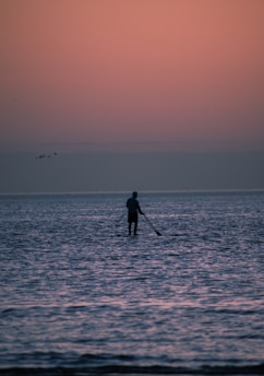 a man standing on a paddle board in the ocean