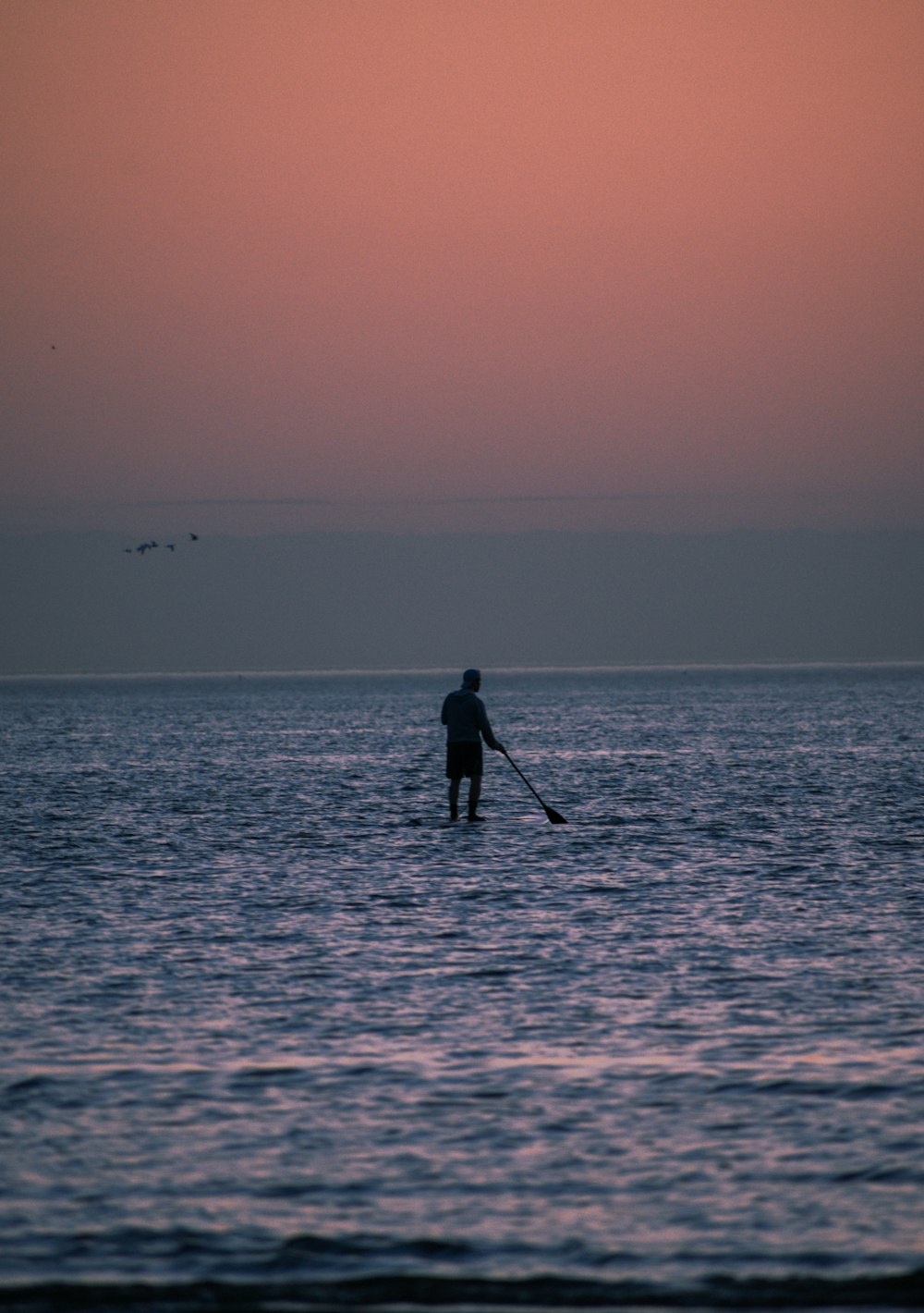 a man standing on a paddle board in the ocean