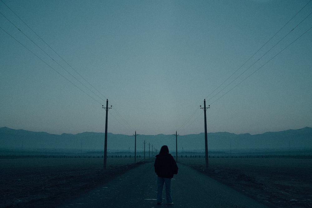 a person walking down a road with power lines in the background