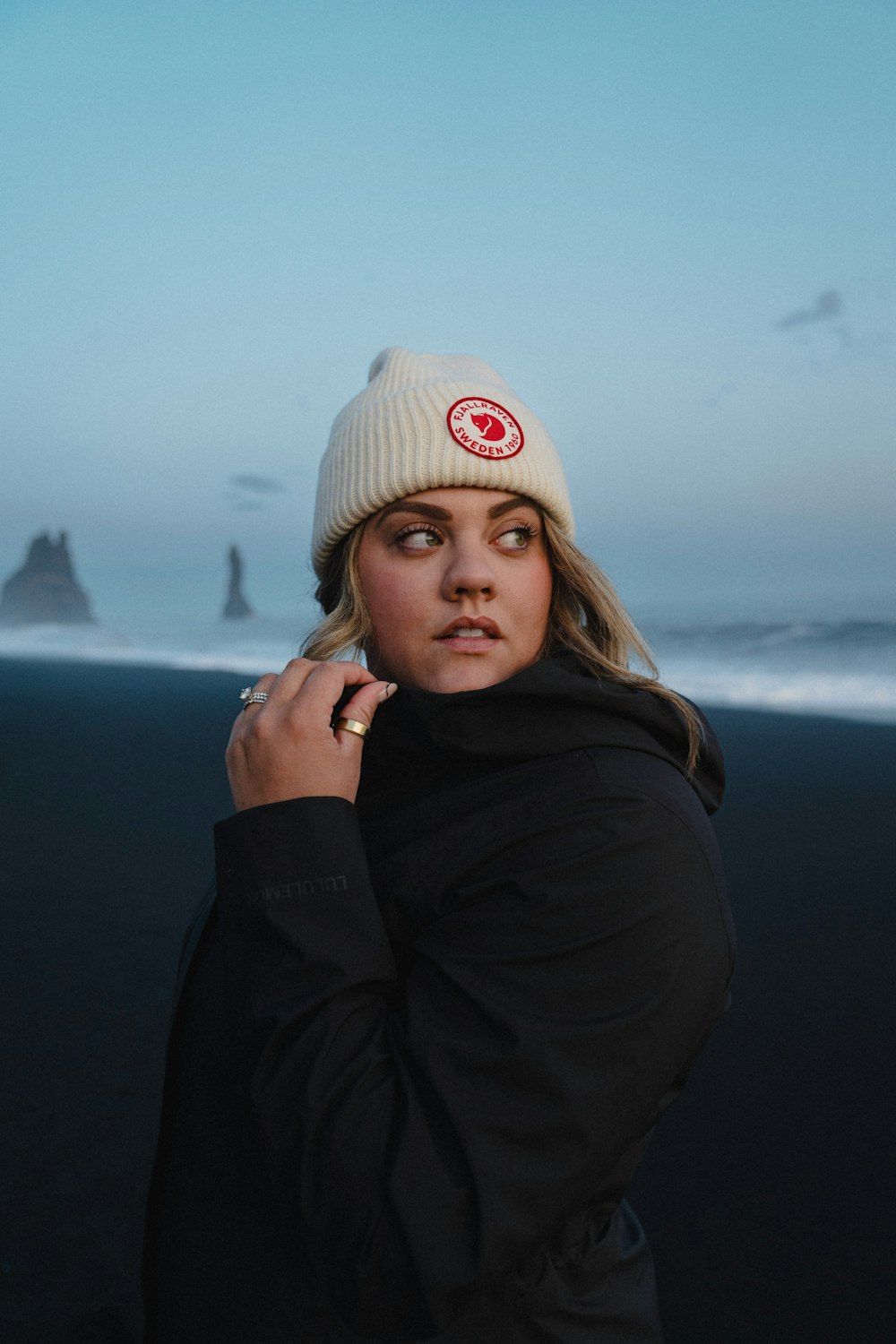 eine frau, die eine mütze trägt, die am strand steht