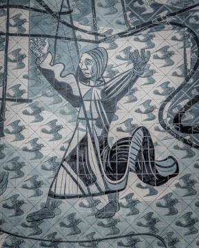 A detailed mural featuring a stylized, abstract figure with outstretched arms and an expression of surprise or wonder. The background is composed of numerous flying birds in a repetitive pattern, contributing to a sense of movement. The artwork uses a mosaic of tiles, each individually painted to form the larger image.