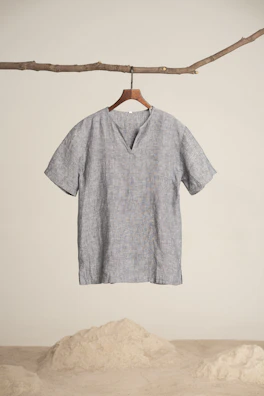 A finished batik shirt displayed on a wooden hanger against a minimalist background.
