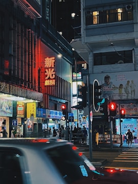 A bustling city street at night with glowing neon signs.