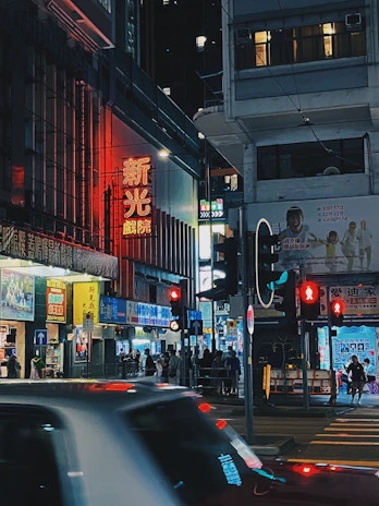 A bustling city street at night, alive with neon signs and movement.