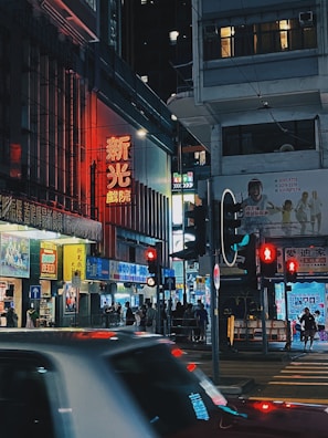 A bustling city street at night, illuminated by colorful neon signs and busy pedestrians.