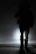 A silhouette of a gothic model standing against a foggy, moonlit backdrop.