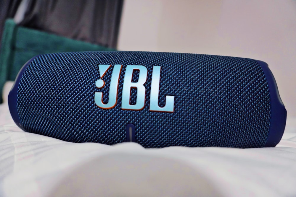 a blue jbl speaker sitting on top of a bed