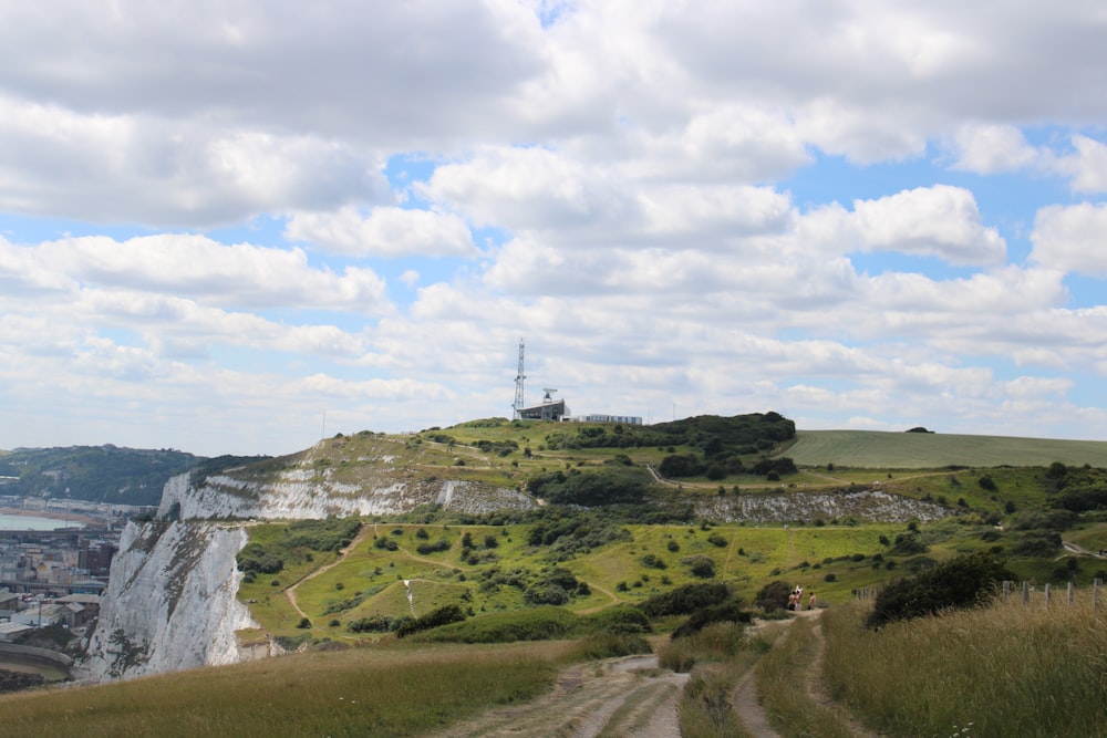 a dirt road on a hill with a tower in the distance