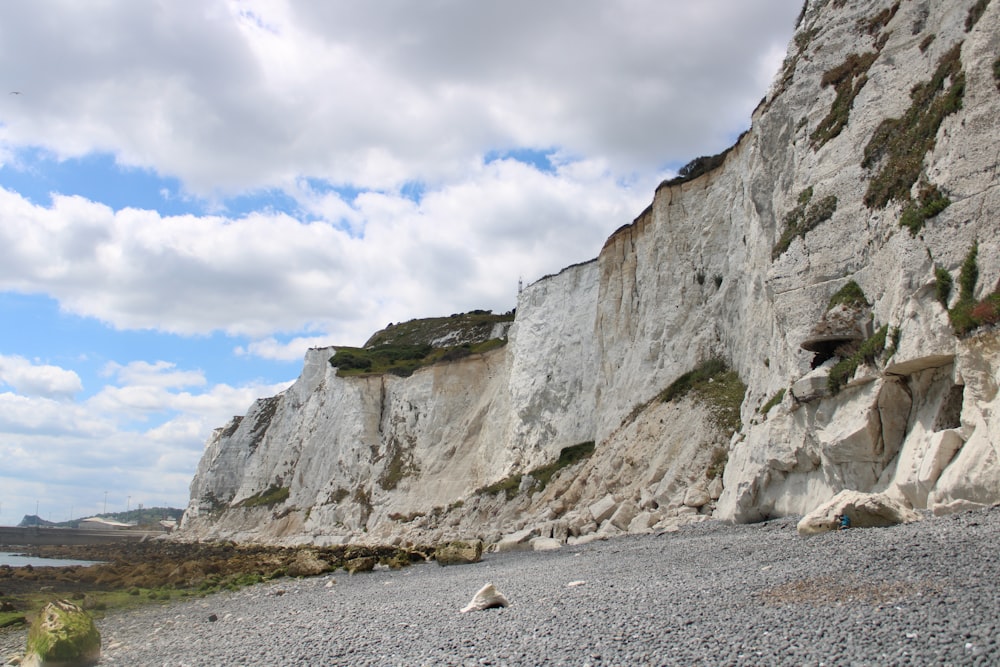 a rocky beach next to a large white cliff