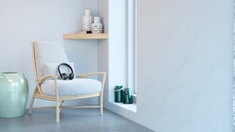 a white chair sitting next to a green vase