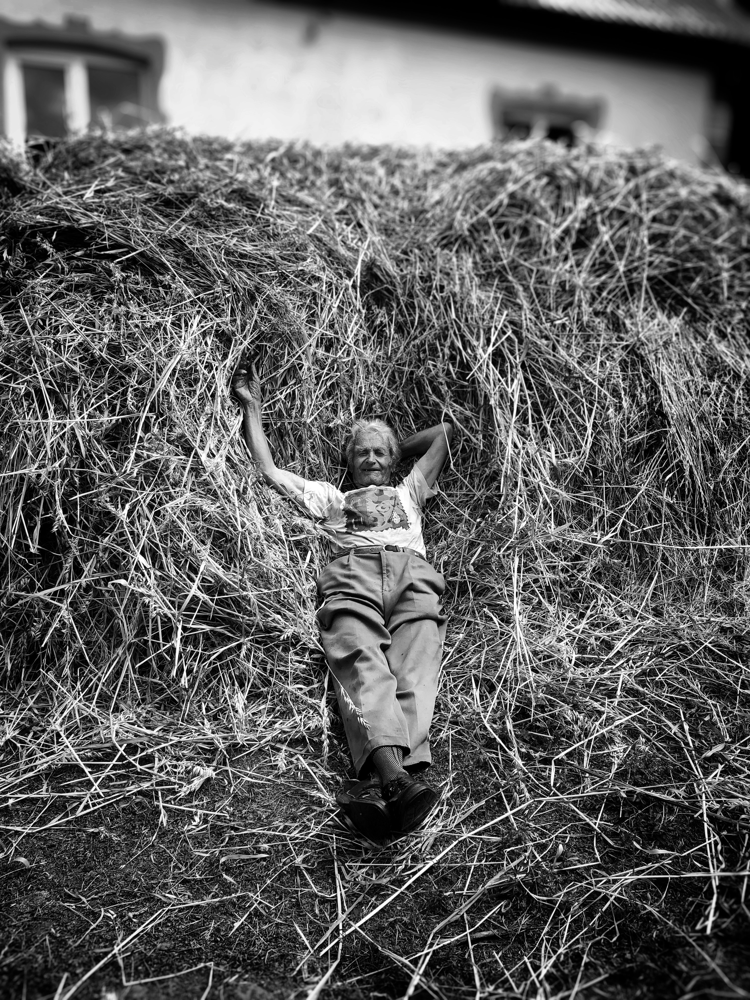 a young boy laying on top of a pile of hay