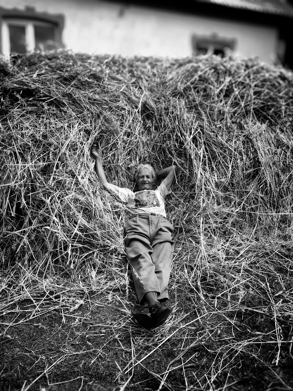 a young boy laying on top of a pile of hay