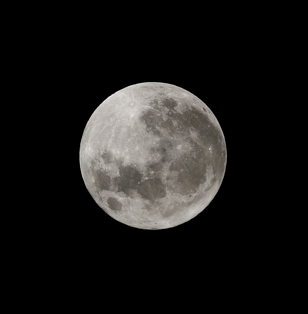 Une pleine lune est vue dans le ciel sombre