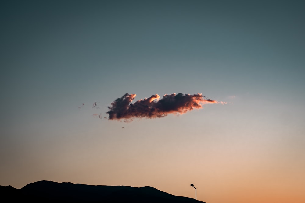 a cloud in the sky above a hill