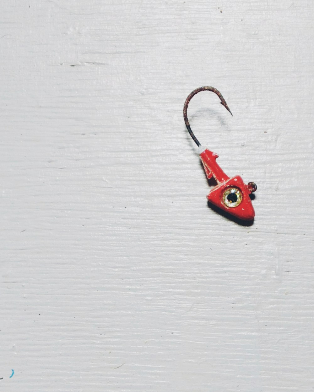 a red fishing hook on a white surface