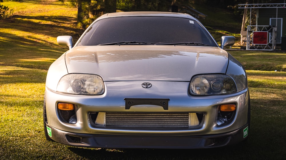 a silver sports car parked in the grass