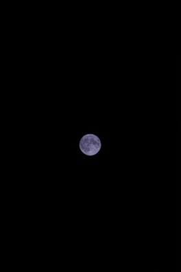 Close-up of the moon’s craters glowing softly in the night sky.