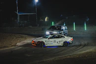 Nighttime shot of race vehicles illuminated by headlights against a starry Baja sky.