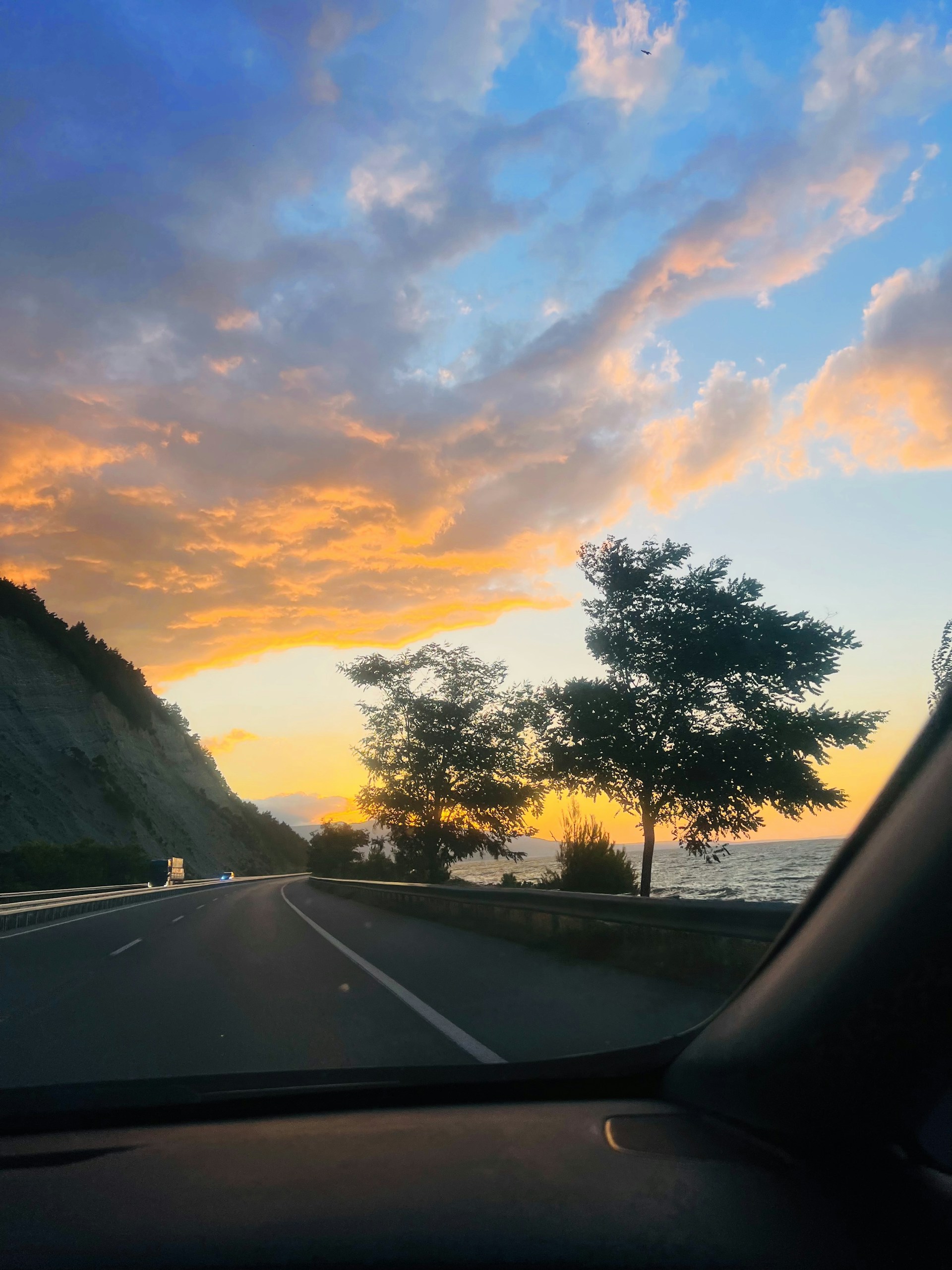 A scenic highway view with a rental car driving along the coast during golden hour